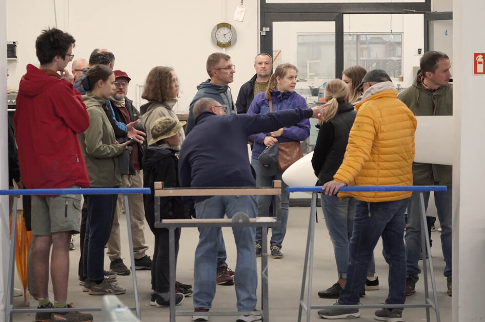 Museumsführer erklärt einer Besuchergruppe etwas im Innenbereich.